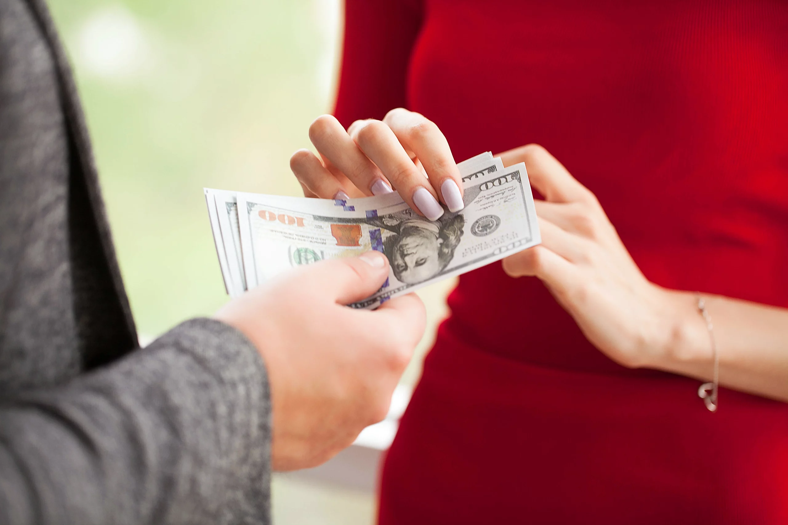 Two people exchanging cash, representing spousal support payments, financial obligations, and alimony calculations under California family law.